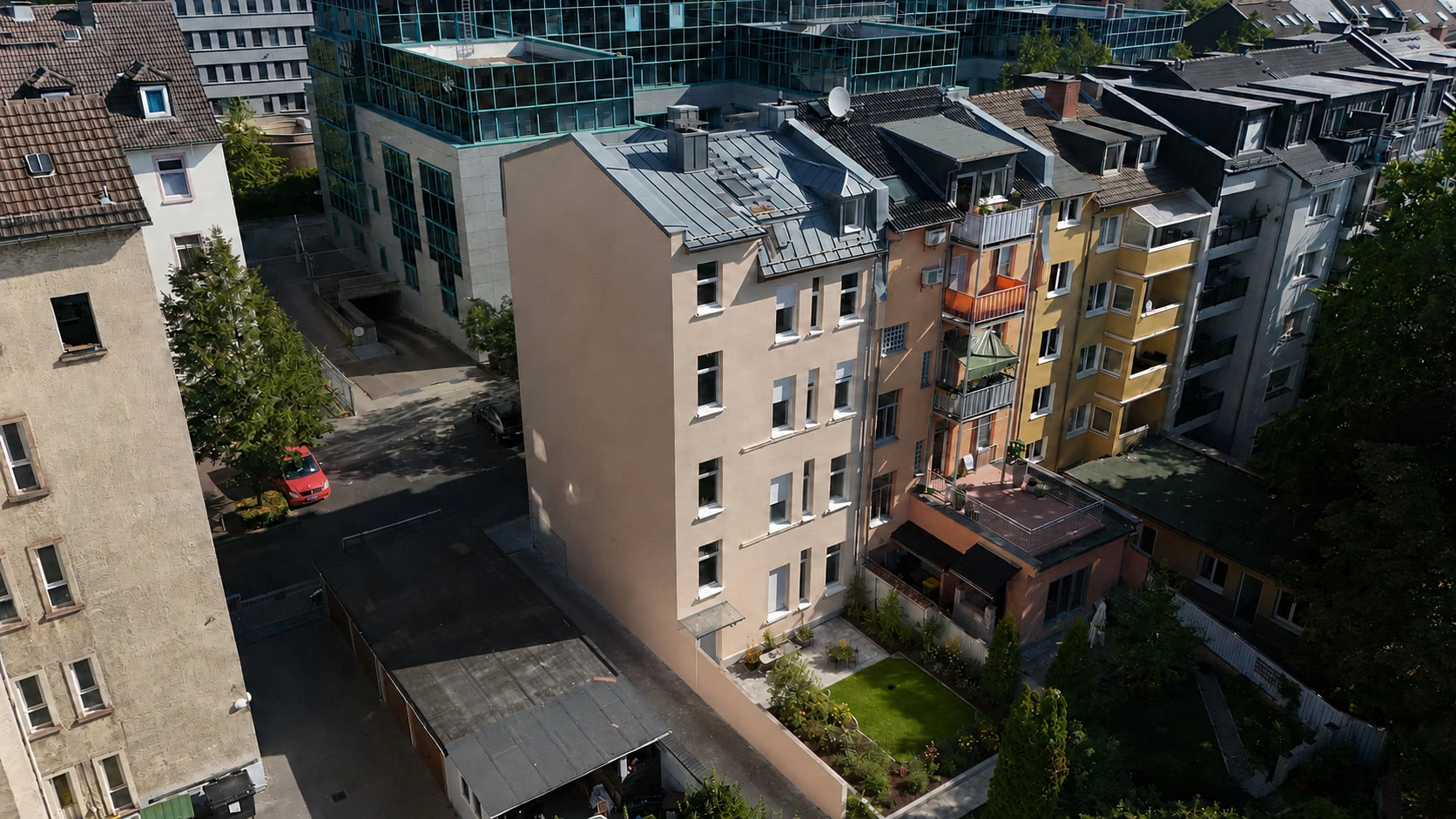 Der Innenhof des Projekts WEST 27 aus der Luft: die sandfarbene Rückfassade mit Balkonen, umgeben von den Nachbarhäusern des Blocks; im Hintergrund ein verglastes Bürogebäude.