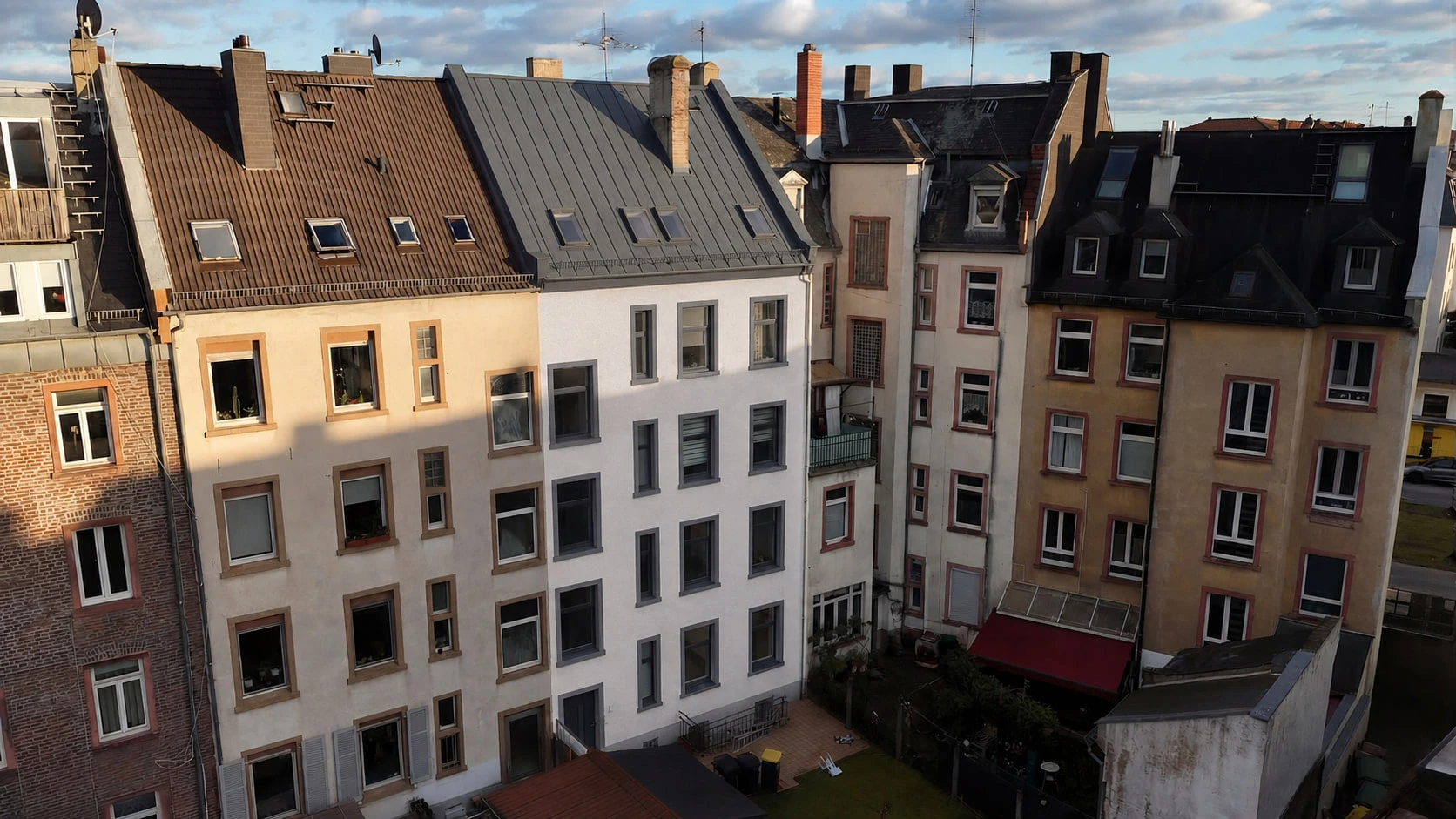 Der Innenhof hinter dem Projekt N°36 aus der Luft: die hellen Rückfassaden des Blocks mit ihren Anbauten und Balkonen, dazwischen begrünte Höfe.