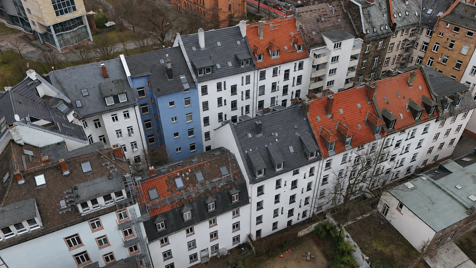 Die Dachlandschaft rund um das Projekt HERITAGE 27 aus der Vogelperspektive: dicht stehende Altbauten mit roten und grauen Dächern, dazwischen die Innenhöfe des Blocks.