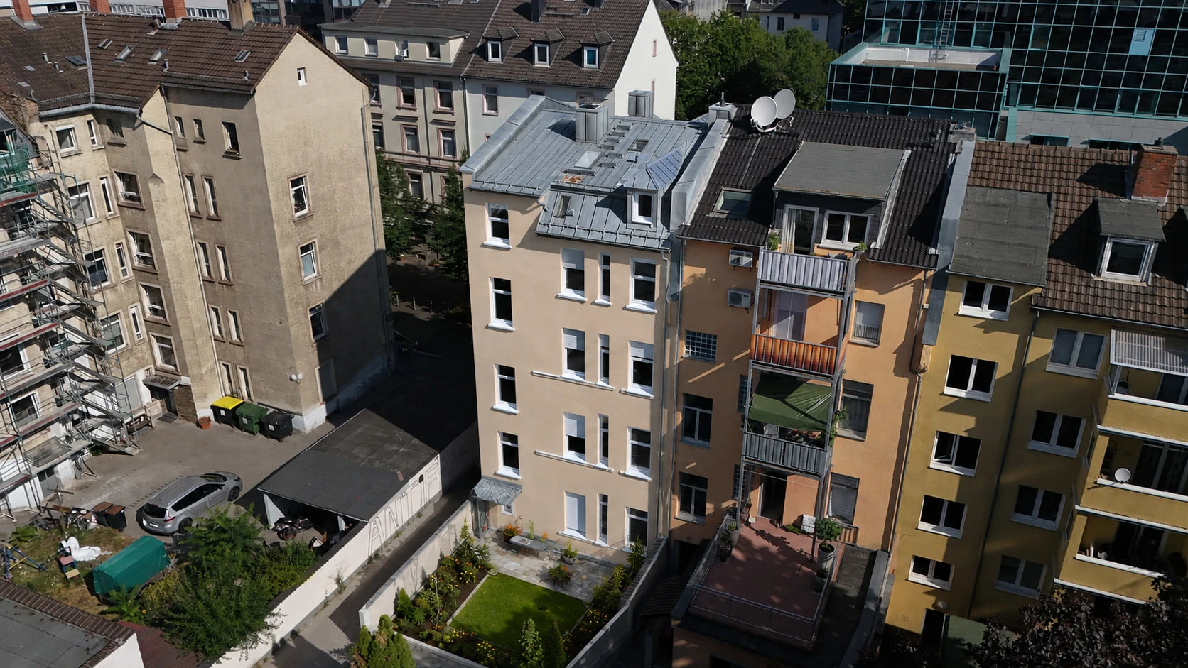 Das Projekt WEST 27 aus der Vogelperspektive über den Dächern: der Altbau in der Häuserzeile, dahinter die begrünten Hinterhöfe und die Nachbarbebauung.