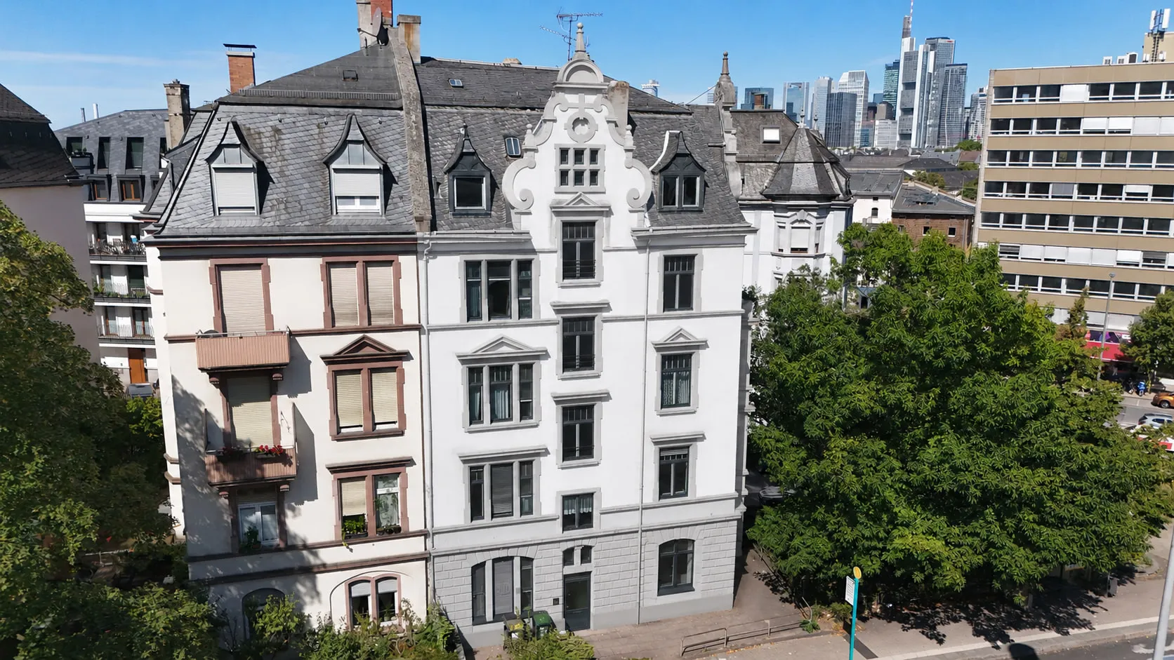 Der Gründerzeitbau CROWN 78 in Schwarzweiß aus der Luft, mit seinem geschweiften Giebel zwischen den Nachbarhäusern der Straße.