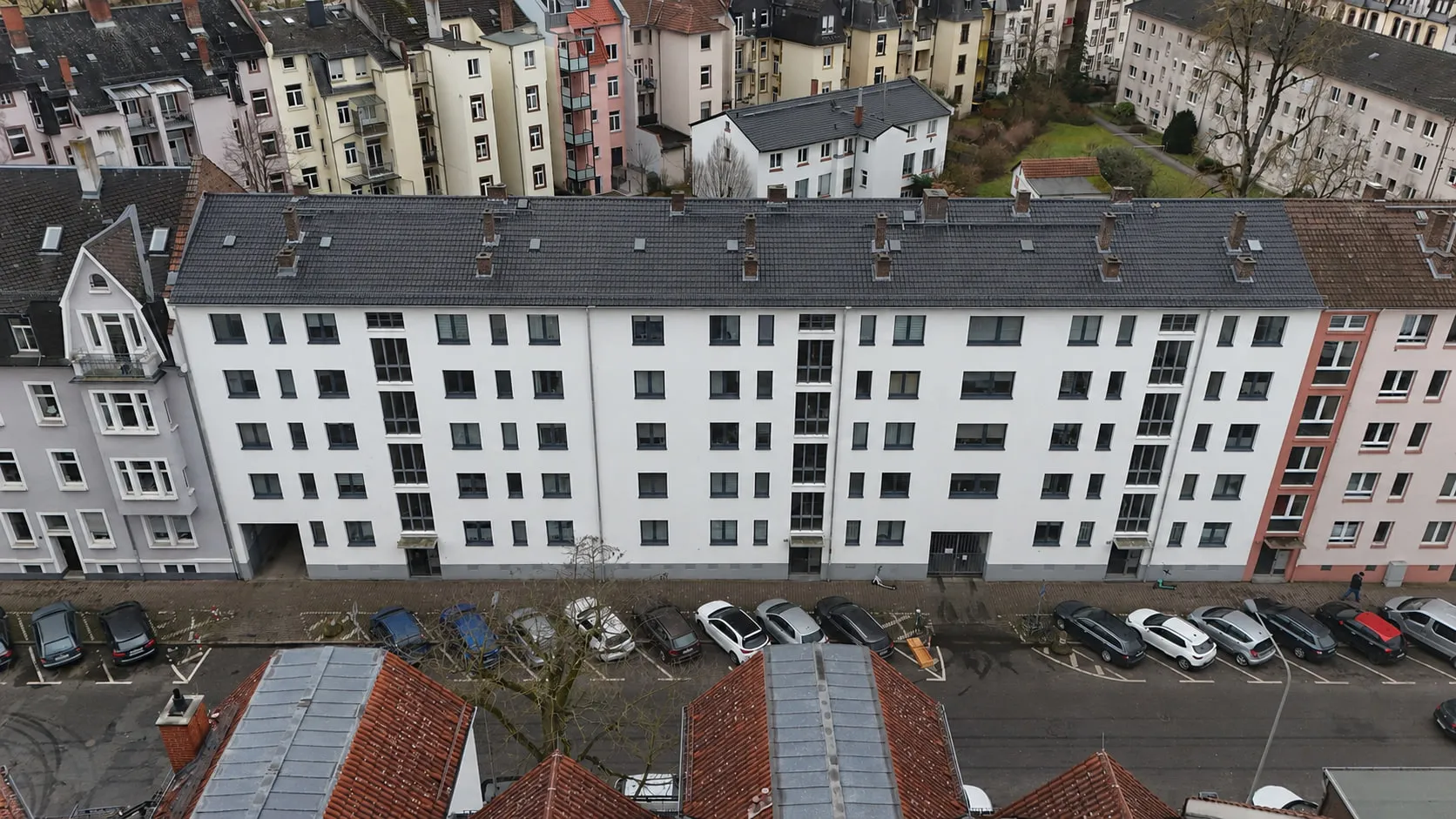 Die lange Wohnzeile ENSEMBLE 27 in Schwarzweiß aus der Luft, über die volle Breite entlang der Straße.