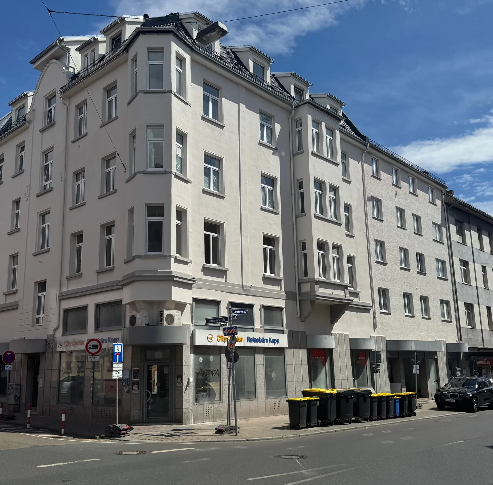 Das Eckhaus CORNER 36 von der Straße aus: die abgeschrägte Gebäudeecke mit übereinanderliegenden Erkern über vier Geschossen, darunter die Ladenzeile im Erdgeschoss, rechts der anschließende Seitenflügel.